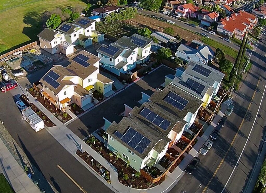 An overhead photo of a new community of homes built by Habitat for Humanity, showing solar panels on the rooftops and landscaped yards.
