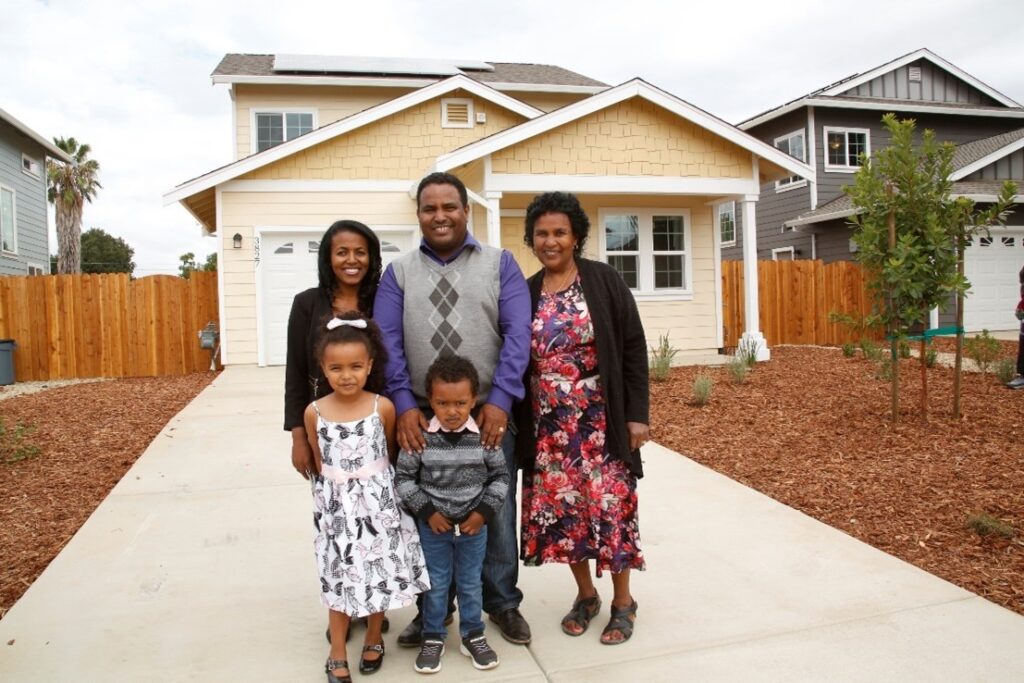 A photo of a family standing in front of a brand new home.